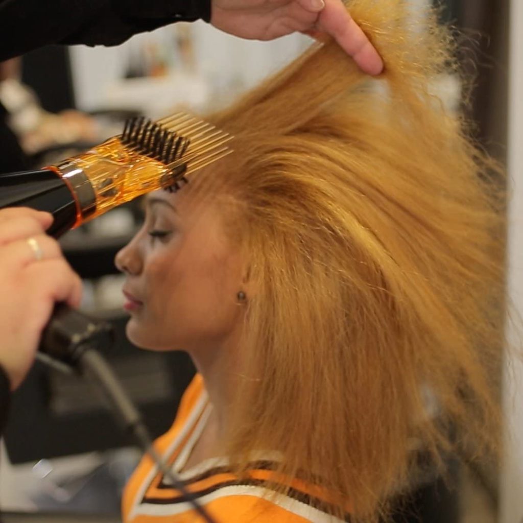 mujer alisando cabello con Los 6 Mejores Secadores de Pelo con Alisador